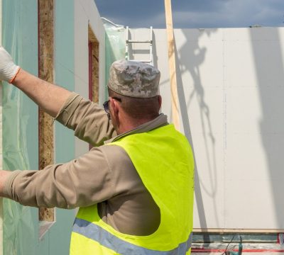Process of construction new and modern modular house from composite sip panels. Workman in special protective uniform wear working on building development industry of energy efficient property